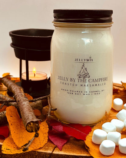 Jellywix candle labeled 'By the Campfire' with marshmallows and autumn leaves on a wooden surface.